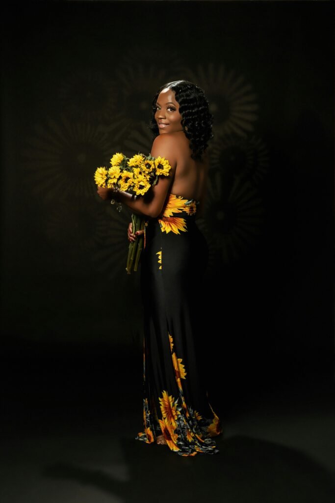 Beautiful woman in sunflower dress holding a bouquet, exuding elegance.