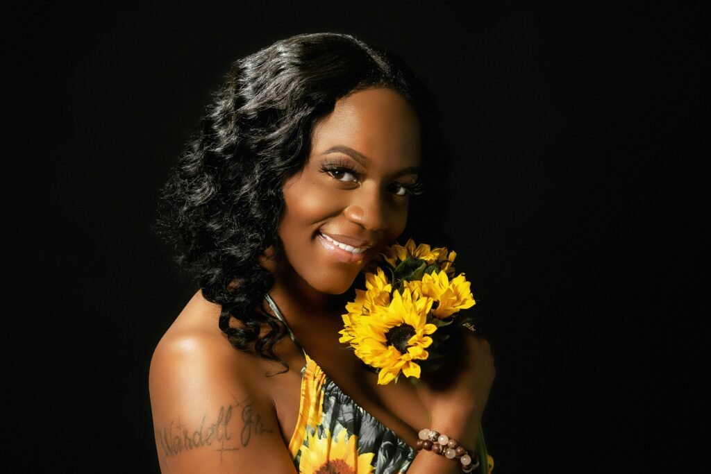 Charming portrait of a woman with sunflowers against a dark background.