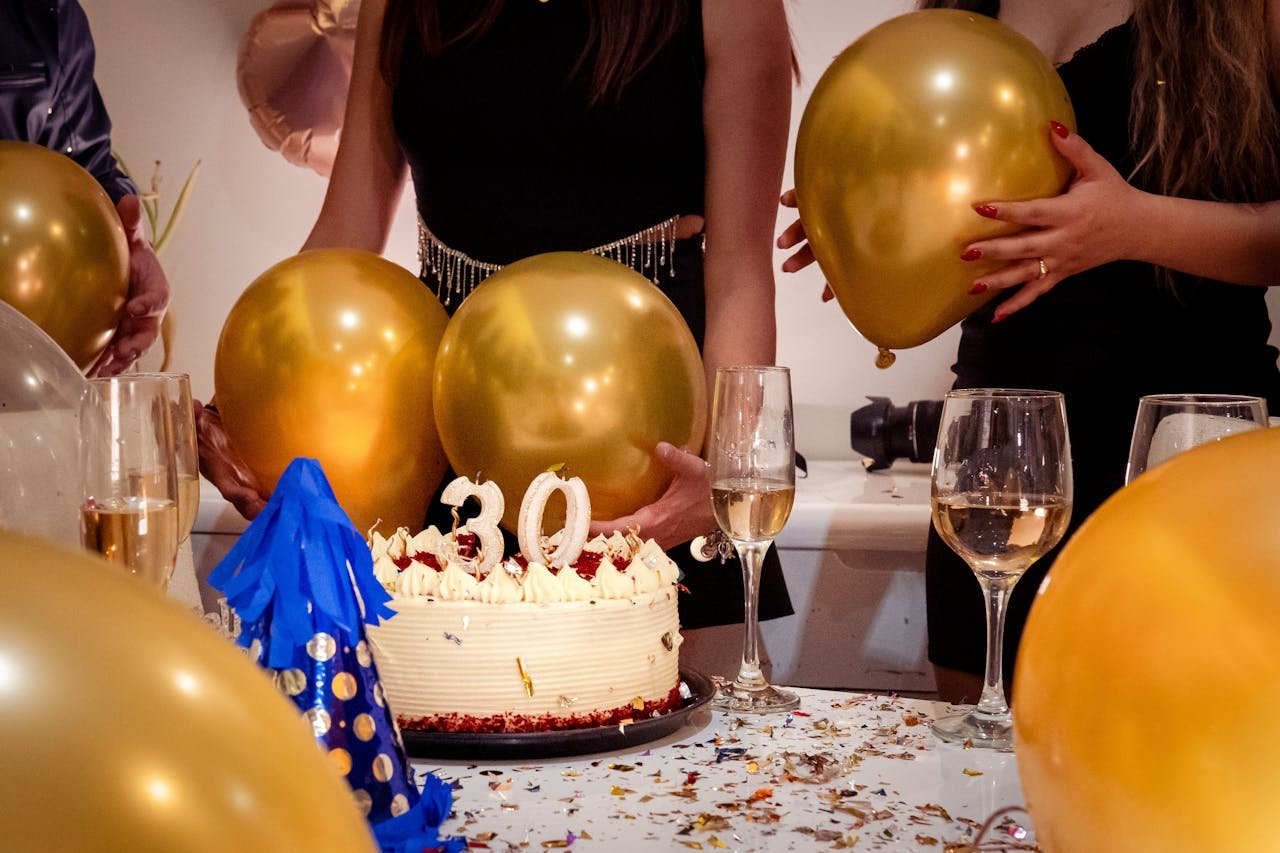 Joyful 30th birthday party with golden balloons, cake, and celebratory drinks.