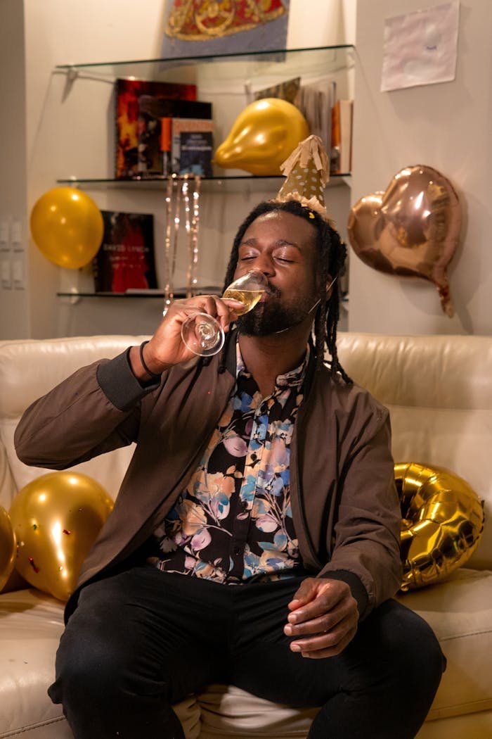 Man enjoying a birthday celebration with champagne and golden balloons indoors.